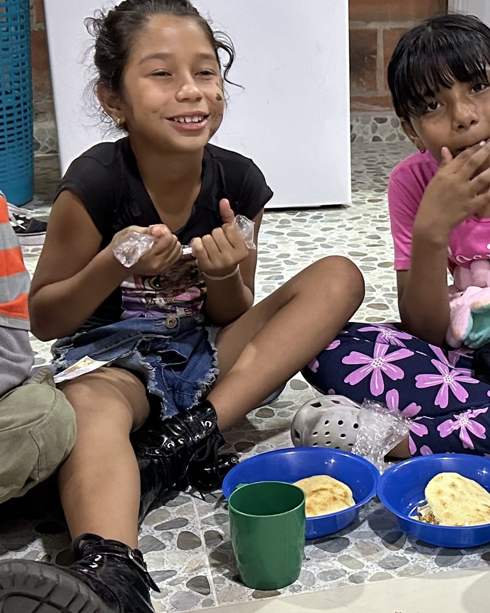 A smiling child sharing a warm meal at a TIKVA gathering in Medellín