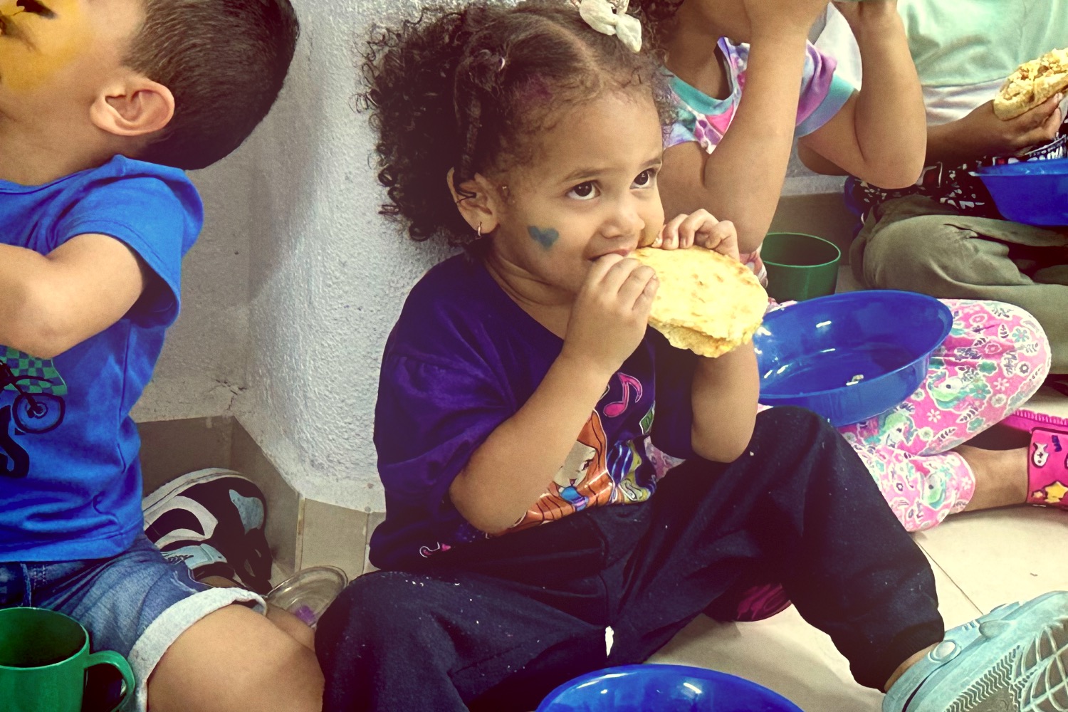 Back of a man at a concert. Hes wearing a beanie hat and a baggy denim jacket with studs. Photo with a purple hue